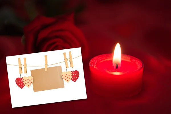 Kerze mit roter Rose gegen weiße Karte — Stockfoto