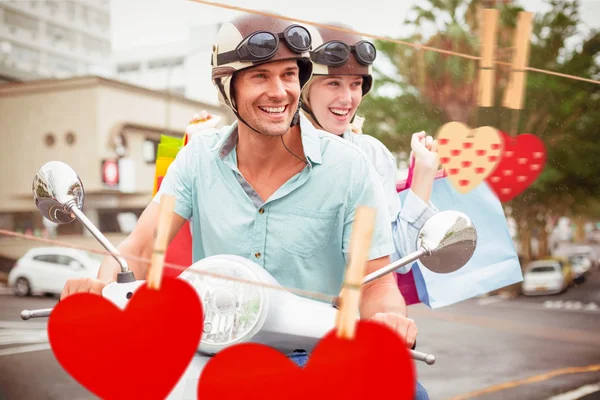 Couple riding scooter with shopping bags — Stock Photo, Image