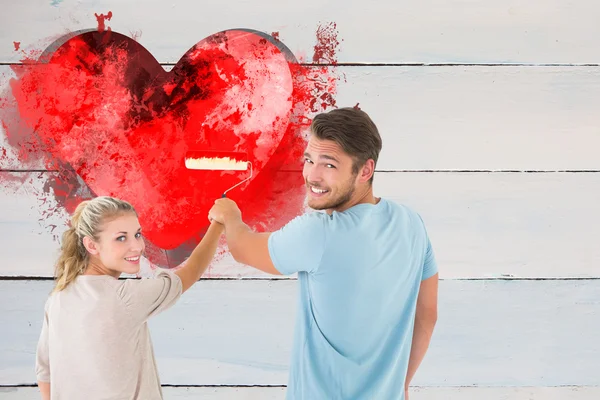 Paar malt mit Walze gegen rotes Herz — Stockfoto