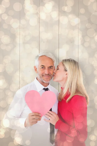 Man holding paper heart getting a kiss from wife — Stock Photo, Image