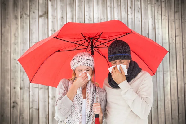 Pareja de moda de invierno estornudando bajo paraguas — Foto de Stock