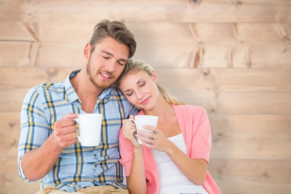 Casal jovem atraente sentado segurando canecas — Fotografia de Stock