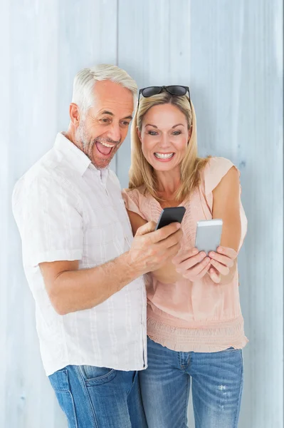 Couple heureux regardant leurs smartphones — Photo