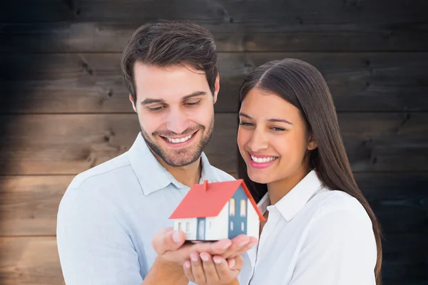Jovem casal segurando uma casa modelo — Fotografia de Stock
