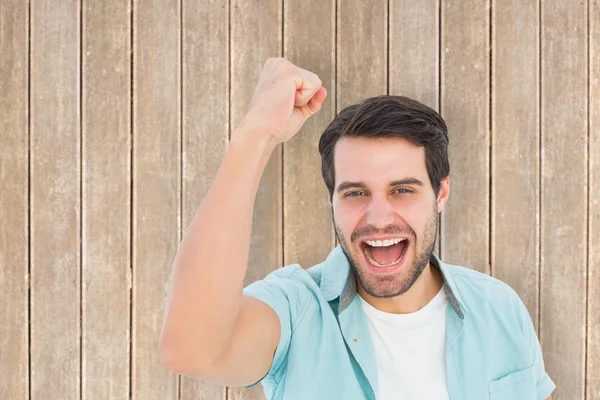 Man cheering at camera against wooden planks — Stock Photo, Image