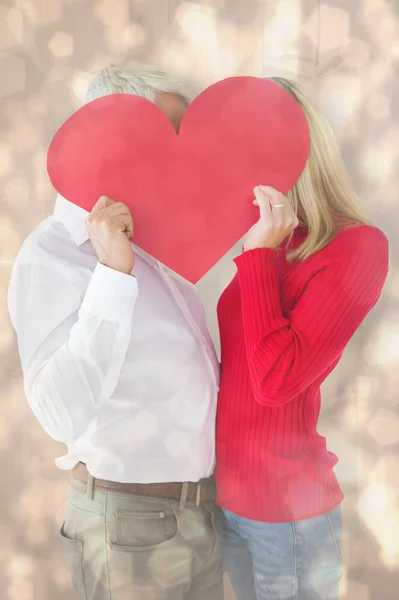 Couple embracing and holding heart over faces — Stock Photo, Image