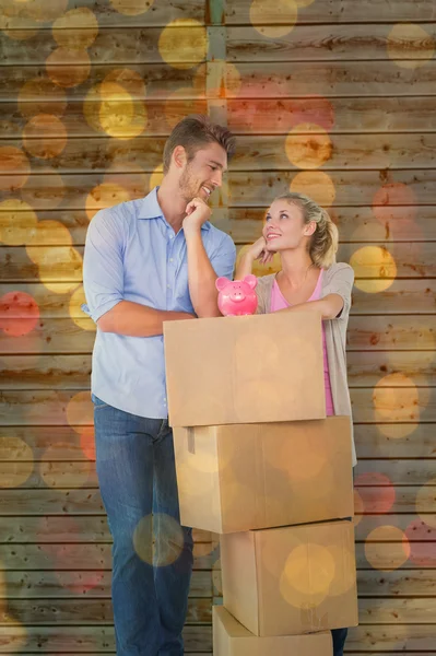 Paar leunend op vakken met piggy bank — Stockfoto