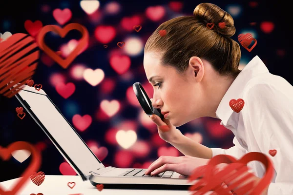 Businesswoman typing and looking through magnifying glass — Stock Photo, Image