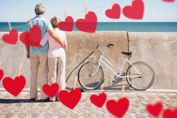 Pareja mirando hacia el mar contra corazones —  Fotos de Stock