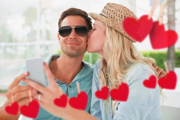 Casal tomando uma selfie juntos contra corações — Fotografia de Stock