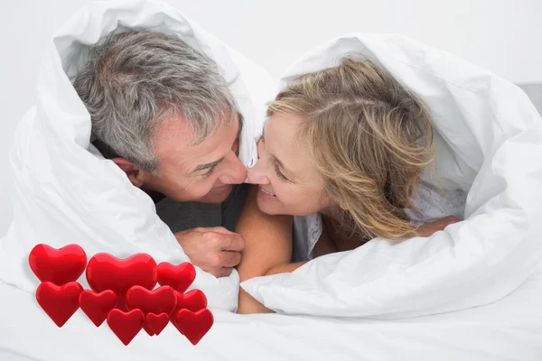 Par under täcket mot love hjärtan — Stockfoto