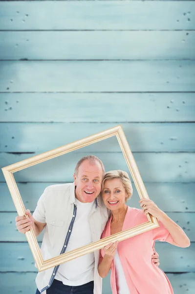 Casal mais velho sorrindo para a câmera através do quadro de imagem — Fotografia de Stock