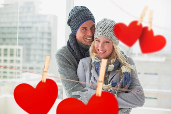 Couple in warm clothing against hearts — Stock Photo, Image