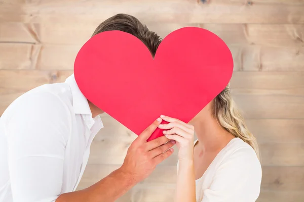 Couple kissing behind large heart — Stock Photo, Image