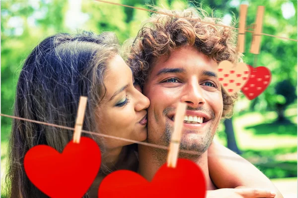 Casal relaxante no banco do parque contra corações — Fotografia de Stock