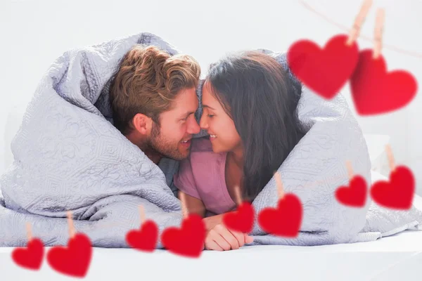 Couple wrapped in the duvet against hearts — Stock Photo, Image