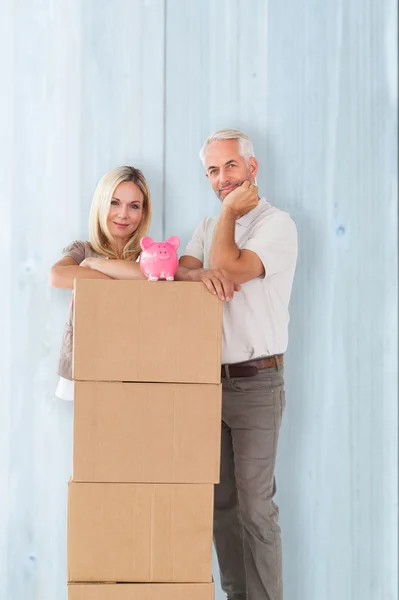 Couple near moving boxes with piggy bank — Stock Photo, Image