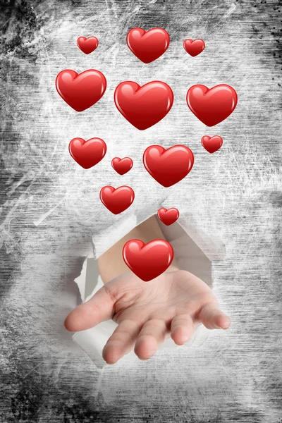 Hand bursting through paper against heart — Stock Photo, Image