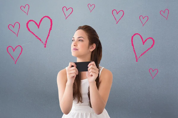 Nachdenkliche Brünette hält ihr Handy — Stockfoto