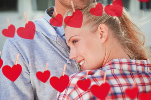 Couple hugging each other against hearts — Stock Photo, Image