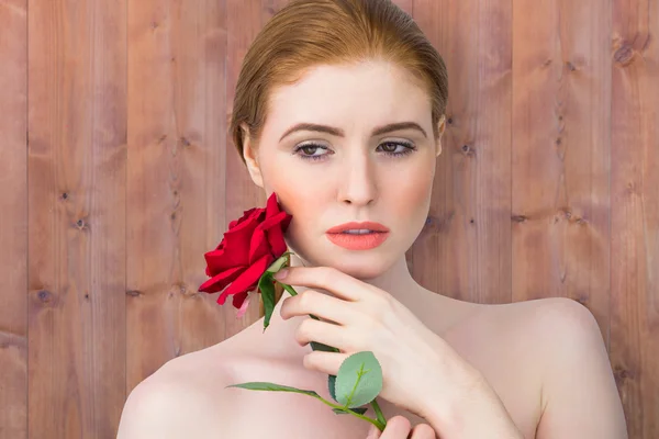 Krásná zrzka pózuje s červenou růží — Stock fotografie