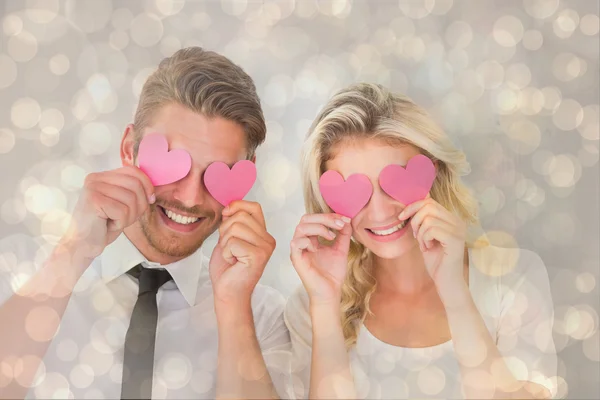 Paar hält rosa Herzen über Augen — Stockfoto