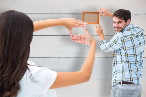 Jovem casal colocando quadro de imagem — Fotografia de Stock