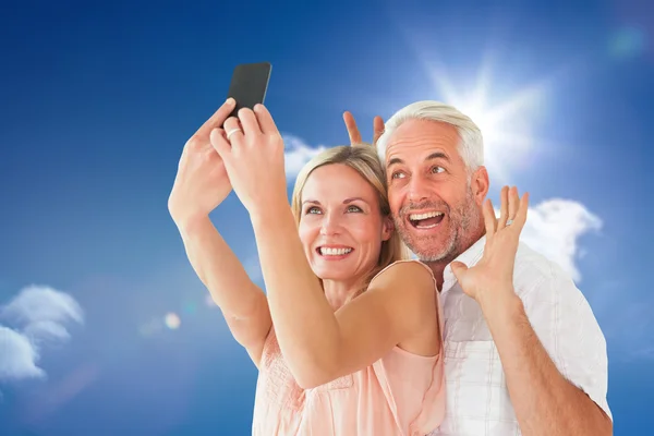 Casal posando para uma selfie contra o céu azul — Fotografia de Stock