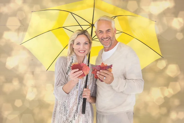 Casal mostrando folhas de outono sob guarda-chuva — Fotografia de Stock