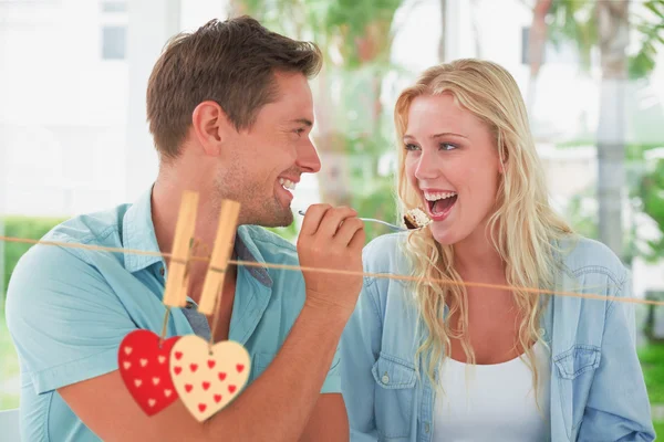 Couple having desert together against hearts — Stock Photo, Image