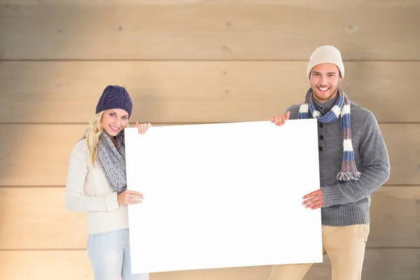 Couple in winter fashion showing poster — Stock Photo, Image