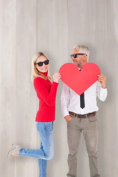 Cool pareja sosteniendo un corazón rojo juntos — Foto de Stock