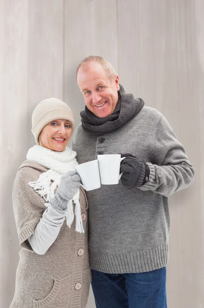 Pareja en ropa de invierno sosteniendo tazas — Foto de Stock