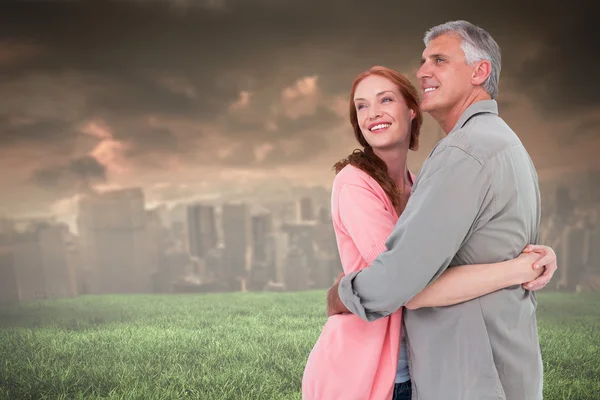 Casal abraçando e sorrindo contra o céu tempestuoso — Fotografia de Stock