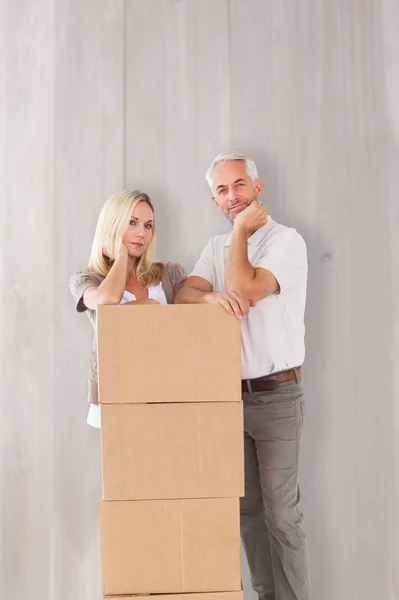 Couple leaning on pile of moving boxes — Stock Photo, Image