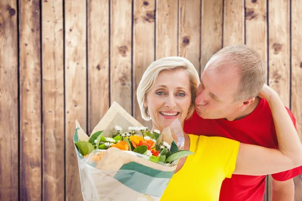 Зрелый мужчина целует своего партнера с цветами — стоковое фото