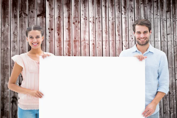 Pár se usmívá na fotoaparát drží plakát — Stock fotografie