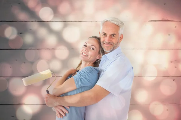 Casal abraçando e segurando rolo de pintura — Fotografia de Stock