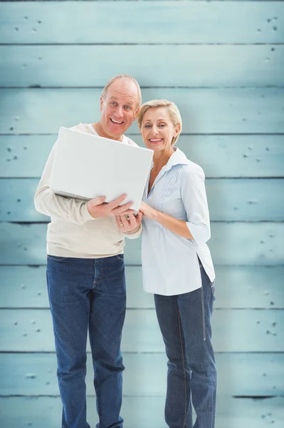 Mature couple smiling at camera with laptop — Stock Photo, Image