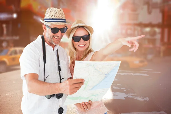 Casal de turistas usando mapa e apontando — Fotografia de Stock