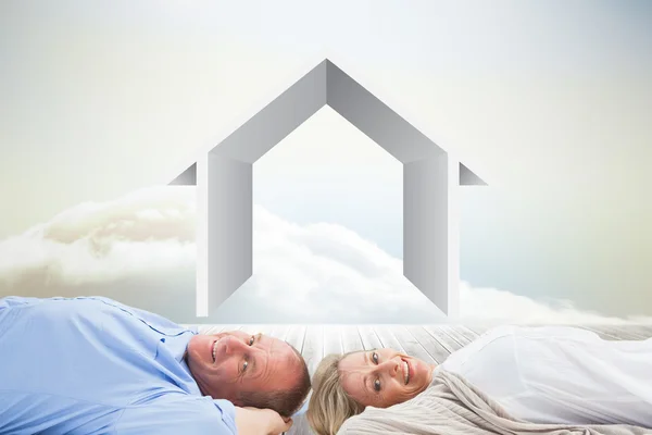 Couple lying and smiling against clouds — Stock Photo, Image