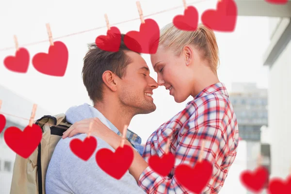 Casal sorrindo um para o outro contra corações — Fotografia de Stock