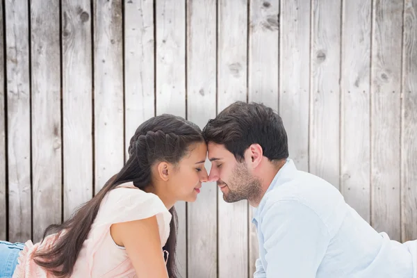 Couple smiling at each other against wooden planks — Stock Photo, Image