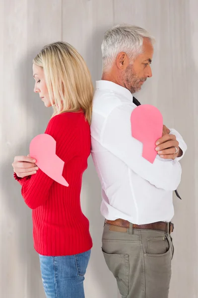 Pareja sosteniendo dos mitades de corazón roto — Foto de Stock