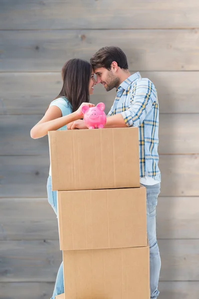 Couple with moving boxes and piggy bank — Stock Photo, Image