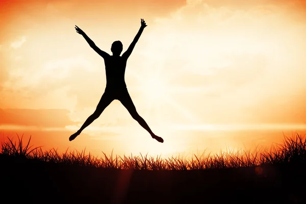 Young woman jumping against orange sunrise — Stock Photo, Image