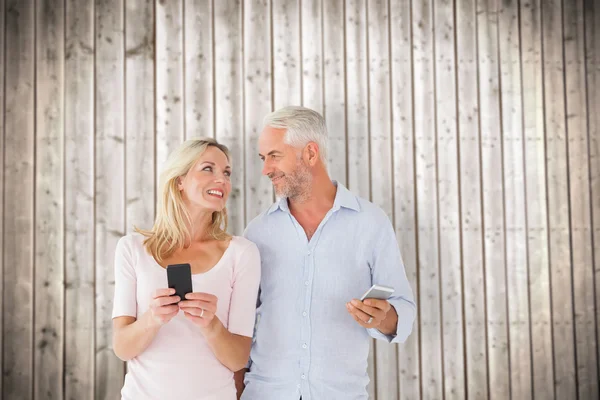 Lyckliga paret textning på deras smartphones — Stockfoto