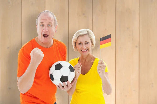 German couple cheering at camera holding ball — Stock Photo, Image