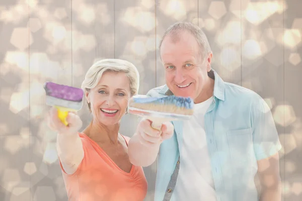 Older couple holding paintbrushes — Stock Photo, Image