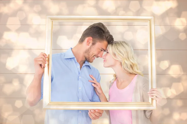 Young couple holding picture frame — Stock Photo, Image